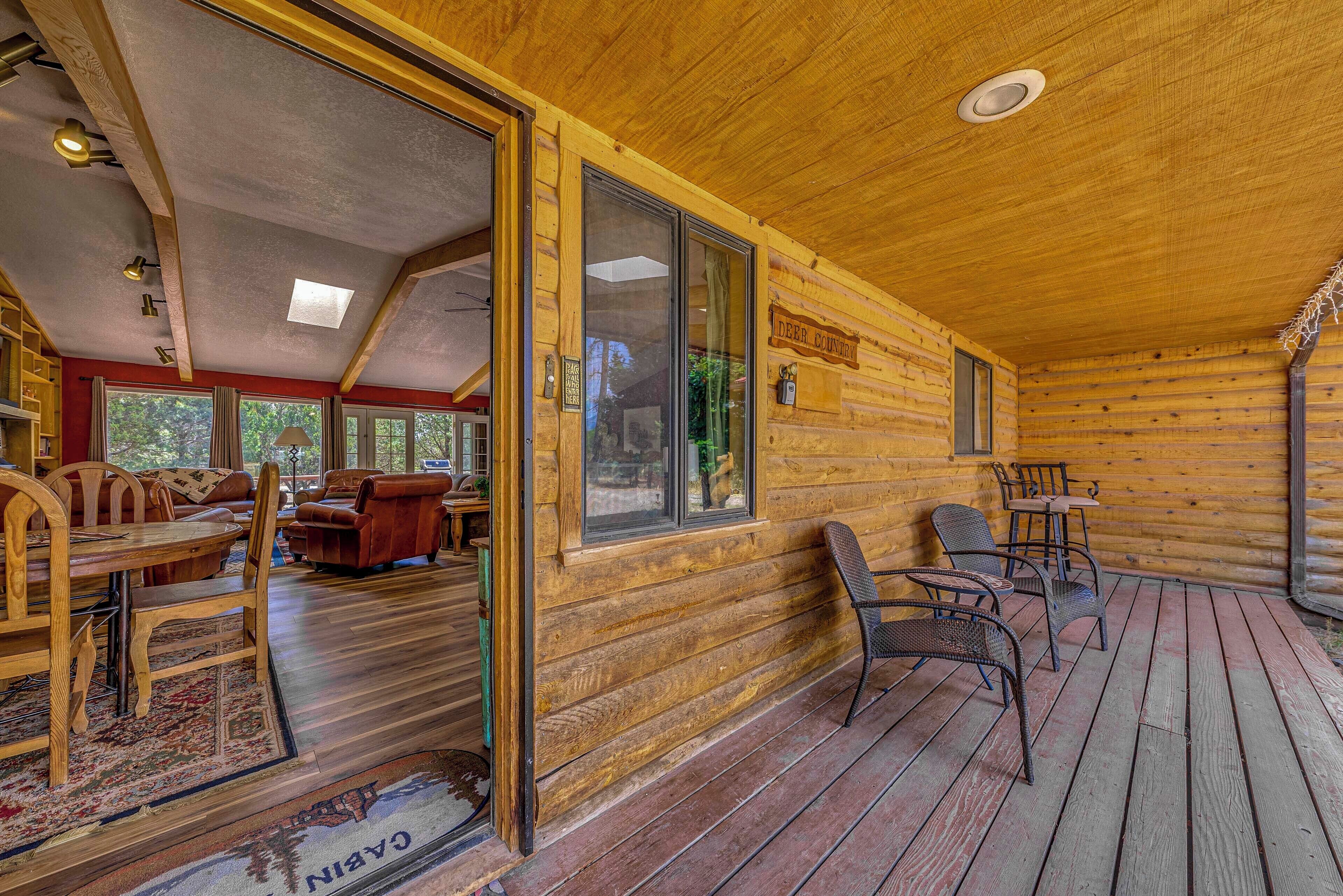 L’intérieur d’une cabane en rondins comprend un coin repas, un canapé et une terrasse avec des sièges d’extérieur.