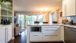Une cuisine moderne dotée d’un îlot central, de meubles blancs, d’un four à micro-ondes encastré et d’un lave-vaisselle.