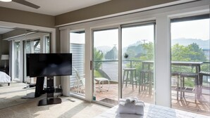 Une chambre d’hôtel comprenant un lit, un téléviseur à écran plat, un balcon avec mobilier d’extérieur et une vue sur le paysage.