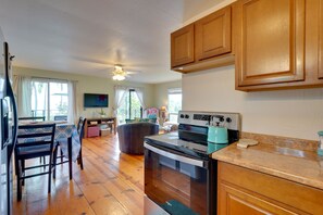 Una cocina con armarios de madera, estufa y comedor con sillas y una mesa.