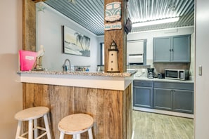 Una cucina con isola in legno, sgabelli da bar, forno a microonde e pensili.