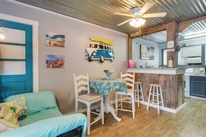Une pièce comprenant un lit, une table à manger avec des chaises, un coin cuisine et des œuvres d’art accrochées aux murs.