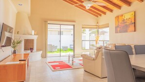 A spacious living room with a wooden ceiling, a fireplace, a sofa, and a dining table.