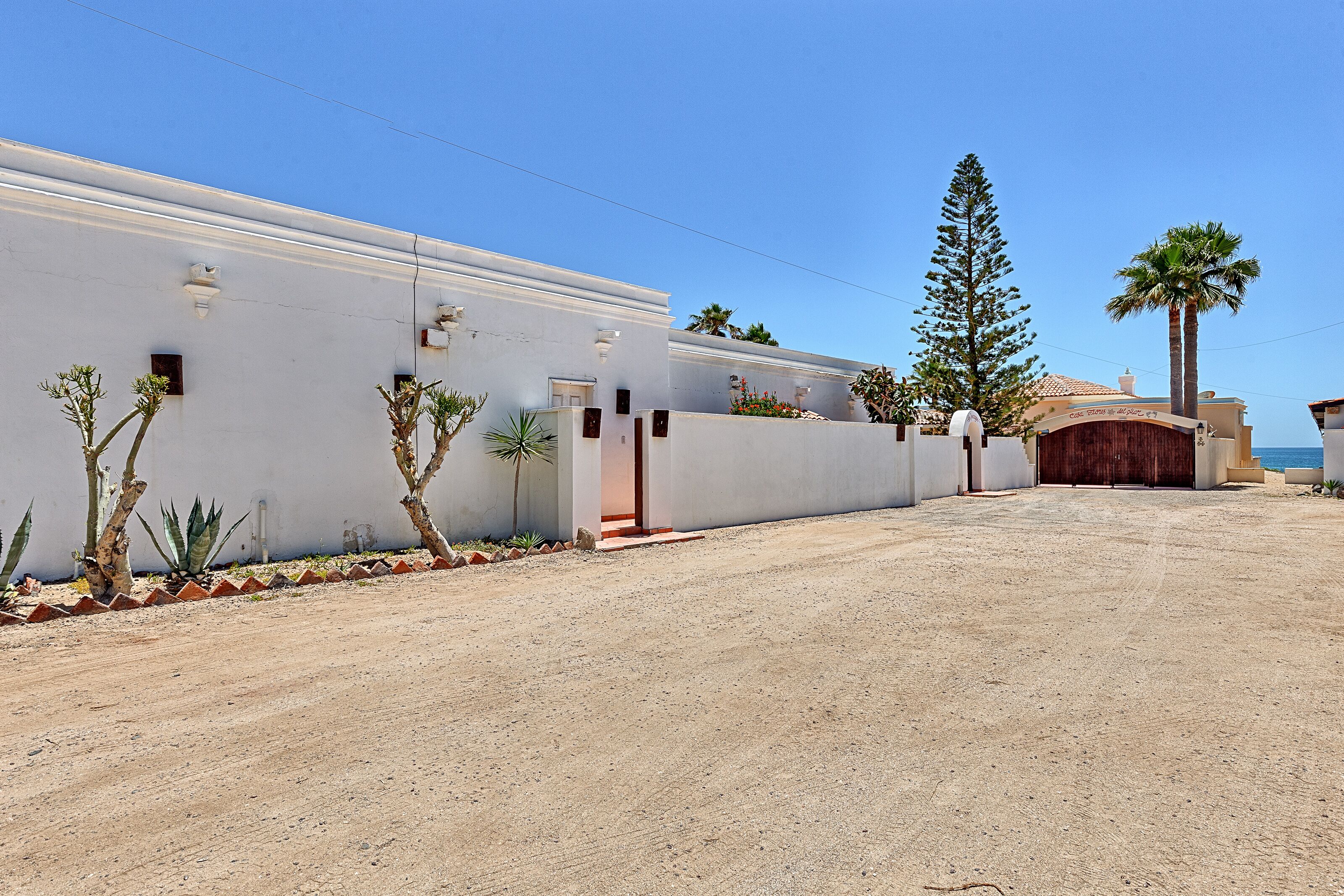 A modern building with a white facade, a wooden door, and a paved driveway.
