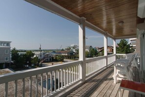 A wooden deck with white railings, overlooking a residential area with houses and a playground.