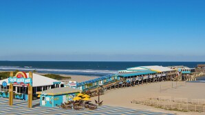 Une jetée donnant sur une plage, sur laquelle se trouve un restaurant appelé Cocoa Beach Pier, offrant des places assises en plein air et une vue sur l’océan.