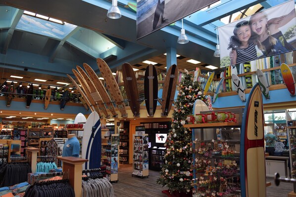 A store with surfboards, a Christmas tree, and various items on shelves.