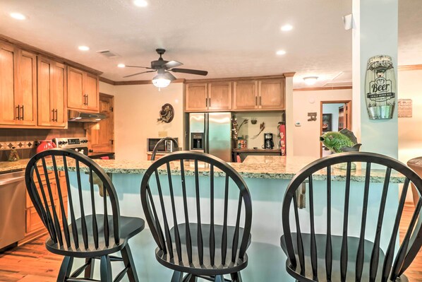 A modern kitchen with wooden cabinets, a stainless steel refrigerator, and a ceiling fan.