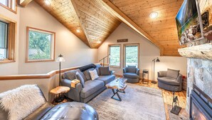 A cozy loft-style living room with a high ceiling, built-in fireplace, and large windows offering views of the outdoors. - Old Town Ski House, Walk to Park City Mountain, Private Hot Tub, AC (Park City)