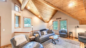 A spacious loft with a high ceiling, large windows, and a cozy seating area with a leather couch, a grey sofa, and a small round table. - Old Town Ski House, Walk to Park City Mountain, Private Hot Tub, AC (Park City)