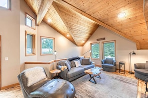 A cozy living room with a sloped ceiling, a grey sofa, a leather armchair, and a coffee table.