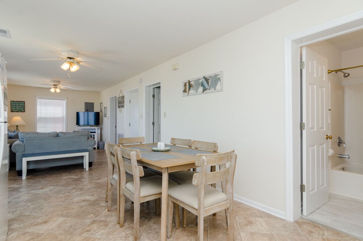A dining area with a wooden table and chairs, a sofa, and a television in the background.