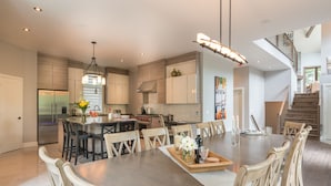 Una cocina moderna con una isla central, electrodomésticos de acero inoxidable y un comedor con una gran mesa de madera y sillas.