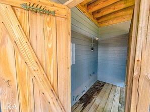 Une cabane en bois avec un petit espace douche fermé.