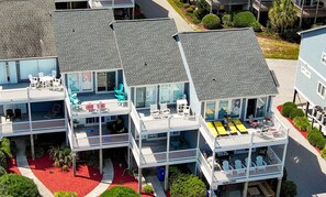 Un immeuble à plusieurs étages doté de balcons, d’un espace extérieur aménagé pour s’asseoir et d’un tapis rouge.