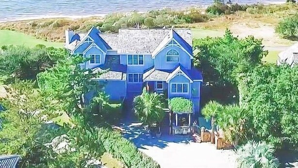 A large, two-story house with a symmetrical facade, multiple windows, and a central entrance. - Doggone Perfect - Village at Nags Head, Soundfront, Golf Course View, Pool, Hot Tub, Pets OK (Nags Head)