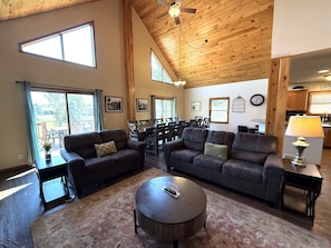 A spacious living room with leather sofas, a coffee table, and a dining area with chairs.