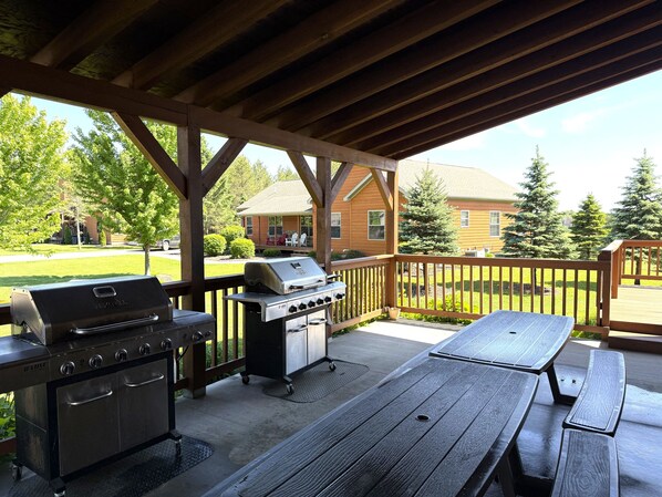 An outdoor patio with a grill, a table, and a covered area.