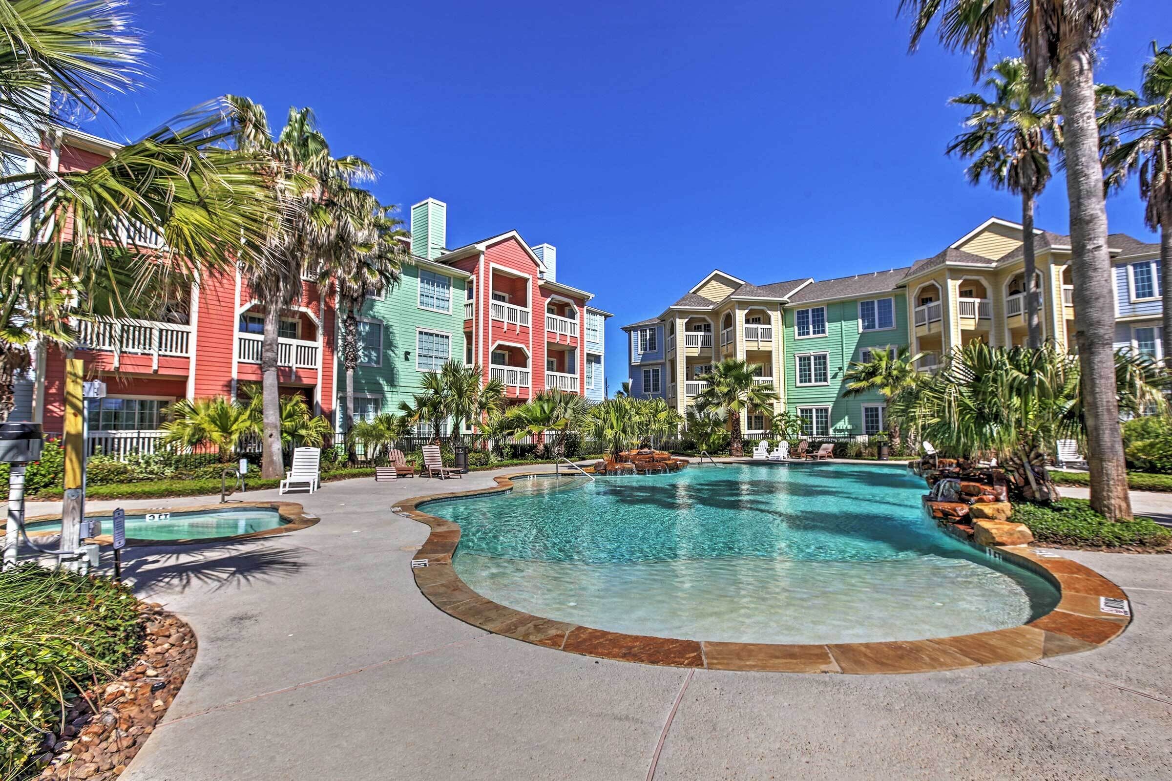 A resort with a large pool, colorful buildings, and palm trees.