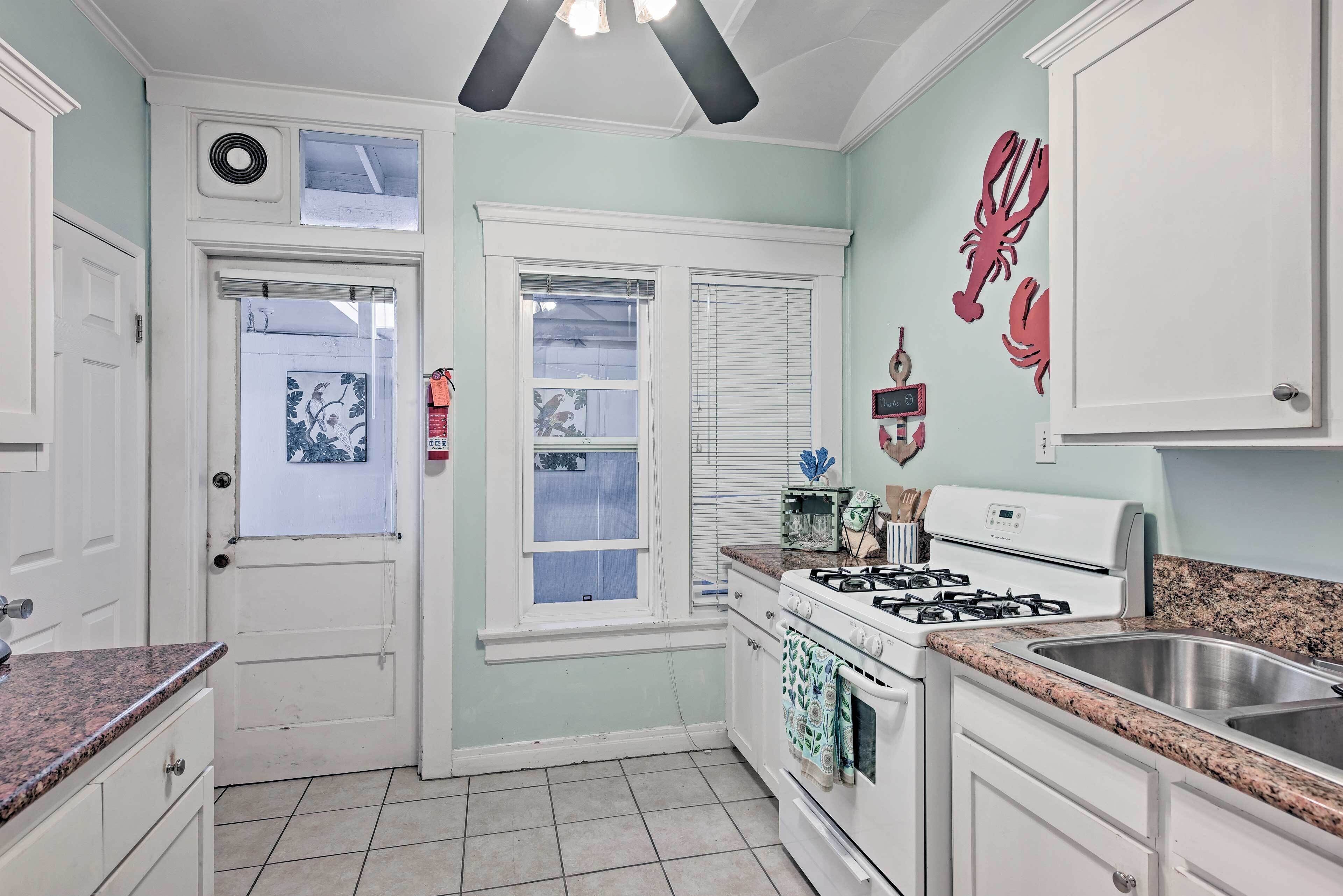 A kitchen with white cabinets, a stove, a sink, and a window with blinds.