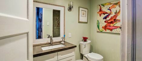 A bathroom with a white toilet, a sink with a mirror, and a trash can.