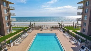 A swimming pool with lounge chairs and a view of the beach. - Ocean view! No drive Beach in New Smyrna Beach! (New Smyrna Beach)
