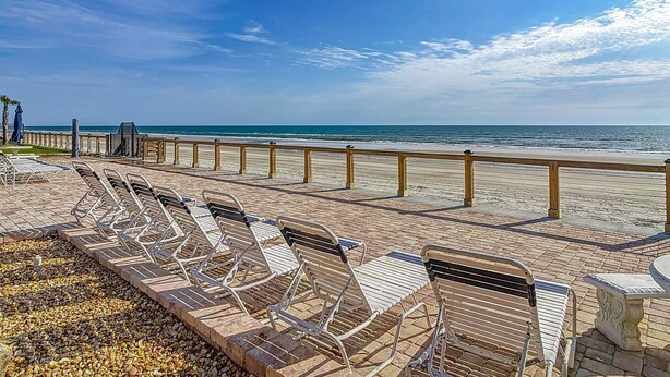 A beachside lounge with sun loungers and a wooden railing overlooking the ocean. - Ocean view! No drive Beach in New Smyrna Beach! (New Smyrna Beach)
