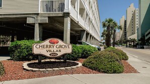 A sign for Cherry Grove Villas, a multi-story building with balconies and a parking garage. - Cherry Grove Villas 204, Golf Villa Bliss near Ocean (North Myrtle Beach)