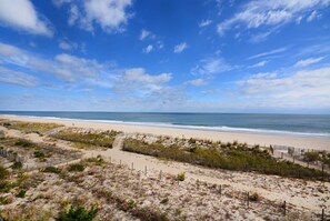 Ein Strand mit blauem Himmel und einem Sandweg zum Wasser.
