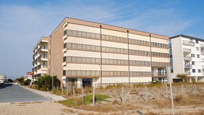 Een hotel met meerdere verdiepingen, een plat dak, balkons en een parkeerplaats ervoor.