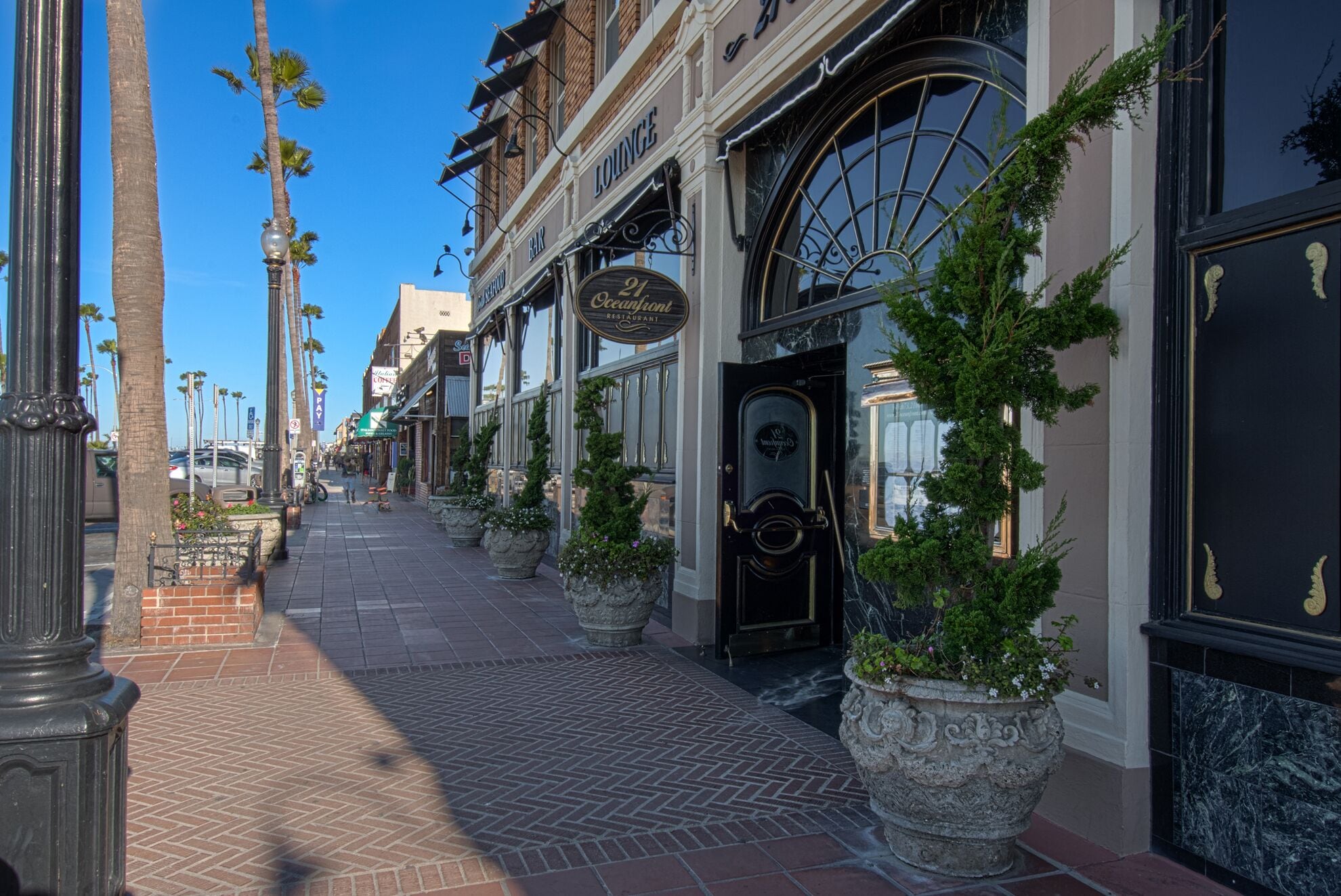 Une rue bordée de boutiques et un restaurant avec une porte noire et de grandes fenêtres.