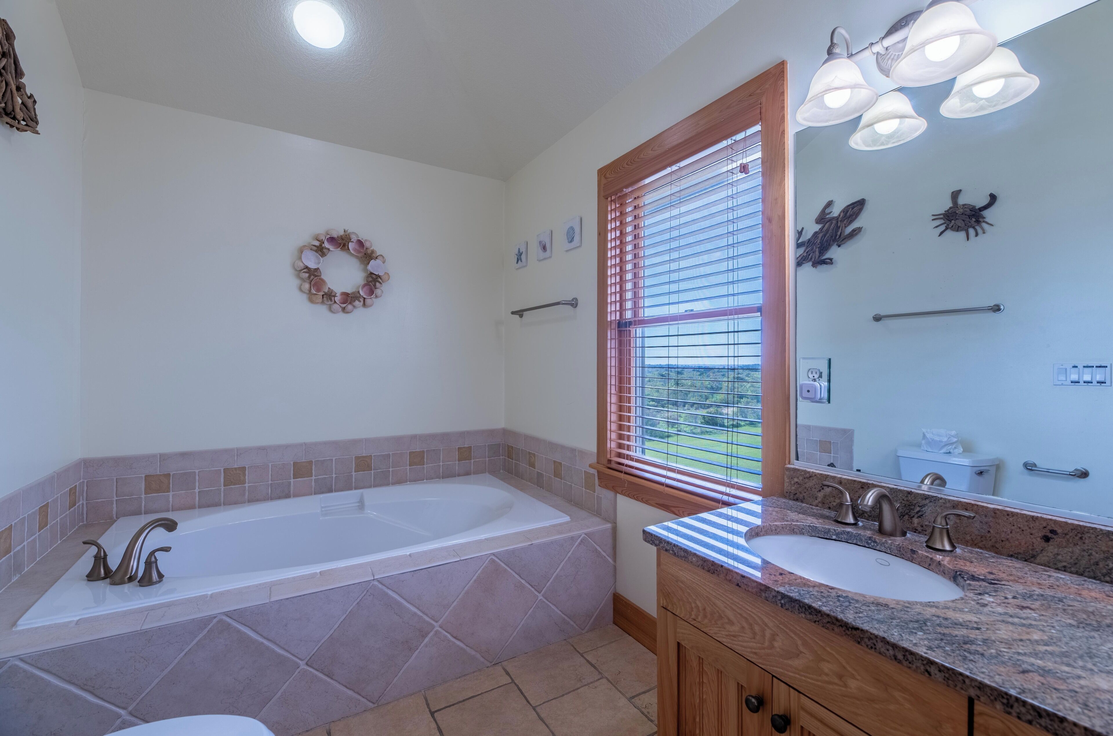 A bathroom with a bathtub, a sink, a vanity, a window with blinds, and a mirror.