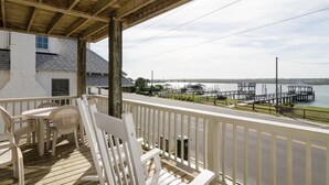 A wooden deck with white railings, overlooking a marina with docks and boats. - Comfortable sound-front duplex near Crystal Pier! (Wrightsville Beach)