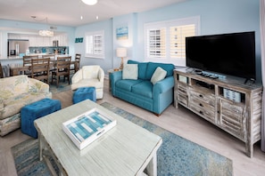 A living room with a dining area, a television, and a kitchen in the background.