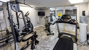 Ein Fitnessstudio mit Cardiogeräten, Krafttrainingsgeräten und einem Fernseher.