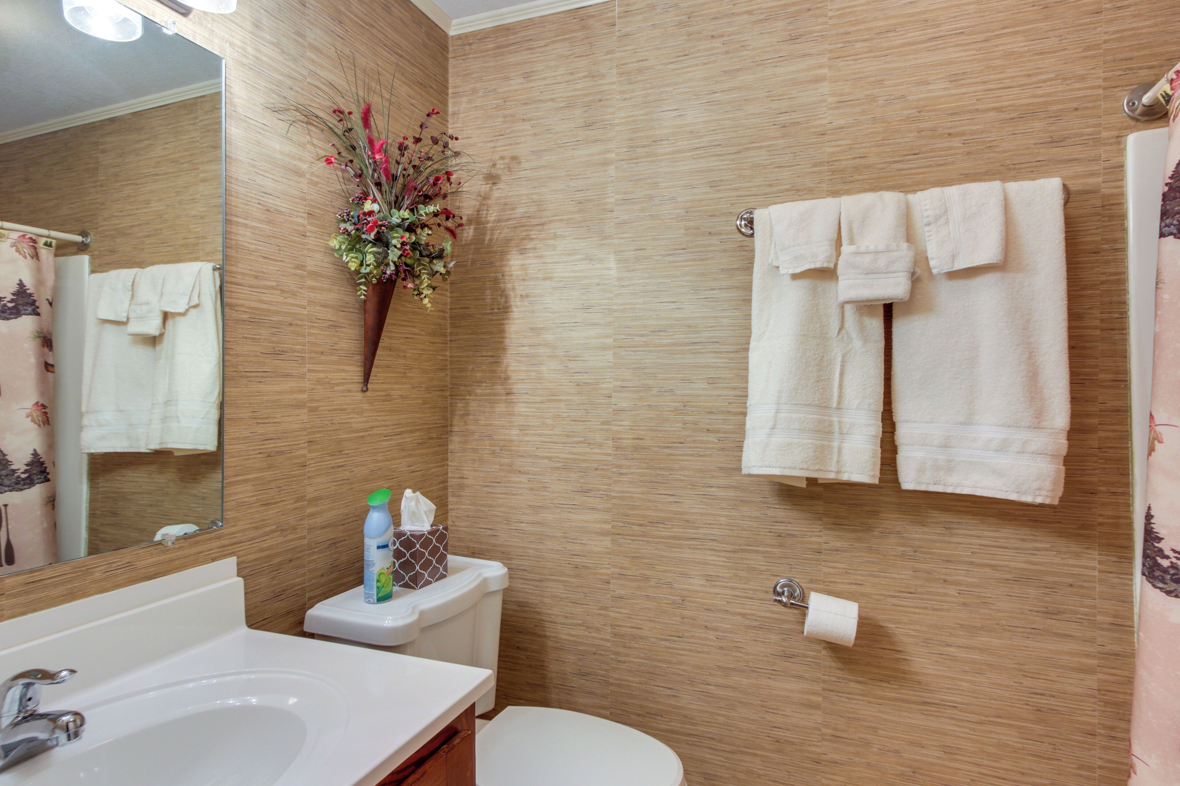 Un baño con pared de madera, un lavabo, un inodoro y un espejo.