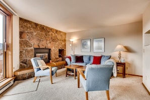 A cozy living room with a stone fireplace, a sofa set, and a coffee table.