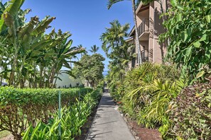 Stroll through lush tropical gardens to a modern building with inviting balconies.