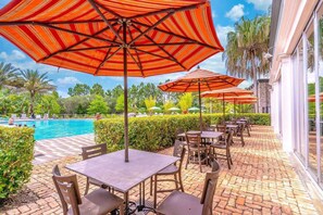 Un espace aménagé au bord de la piscine, avec des sièges et des parasols.