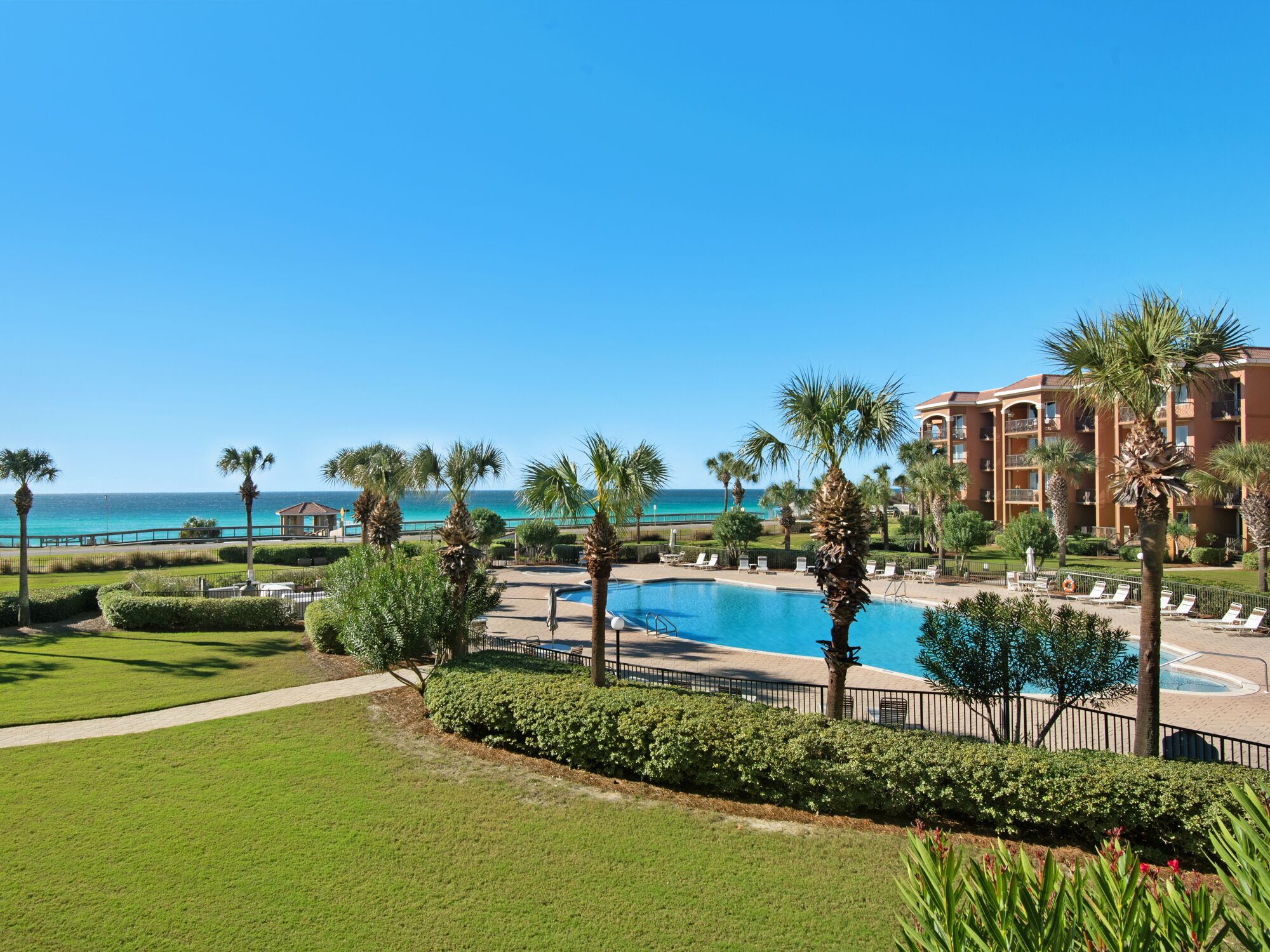 A resort with a swimming pool, palm trees, and a view of the ocean.