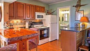 Una cocina con armarios de madera, microondas, estufa y refrigerador.