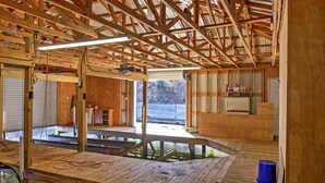 Una habitación amplia con techo alto, vigas de madera y un ventanal grande.