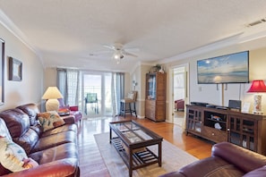 Relax in this stylish living room with a leather sofa, flat-screen TV, and sliding glass door to an outdoor patio.