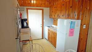 A small kitchen with wooden cabinets, a white refrigerator, a stove, and a coffee maker. - SN9017D- Semi-OF!  With 3 BRs, Direct Beach Access, Private and Secluded! (Nags Head)