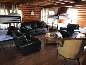 Ein gemütliches Blockhaus-Interieur mit Etagenbett, Leder Möbeln und Holzboden.