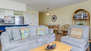 A living room with a grey sofa, a coffee table, and a dining area with a table and chairs.