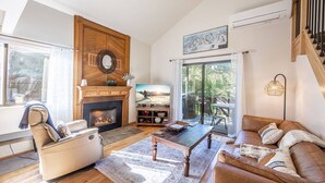 A cozy living room with a fireplace, a sofa, a coffee table, and a television. - Canyons Resort 2BR | 2-Mins to Cabriolet | Free On-Call Shuttle | Hot Tubs | Updated Redpine Condo (Park City)