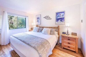 Une chambre à coucher avec un grand lit, une tête de lit en bois, des tables de chevet avec des lampes et des tableaux encadrés accrochés au mur.