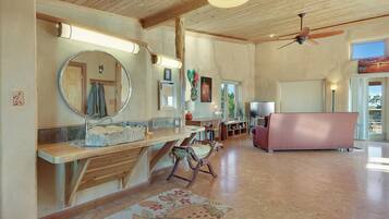 A spacious living room with a wooden ceiling, a large mirror, a sofa, and a dining area with a table and chairs.