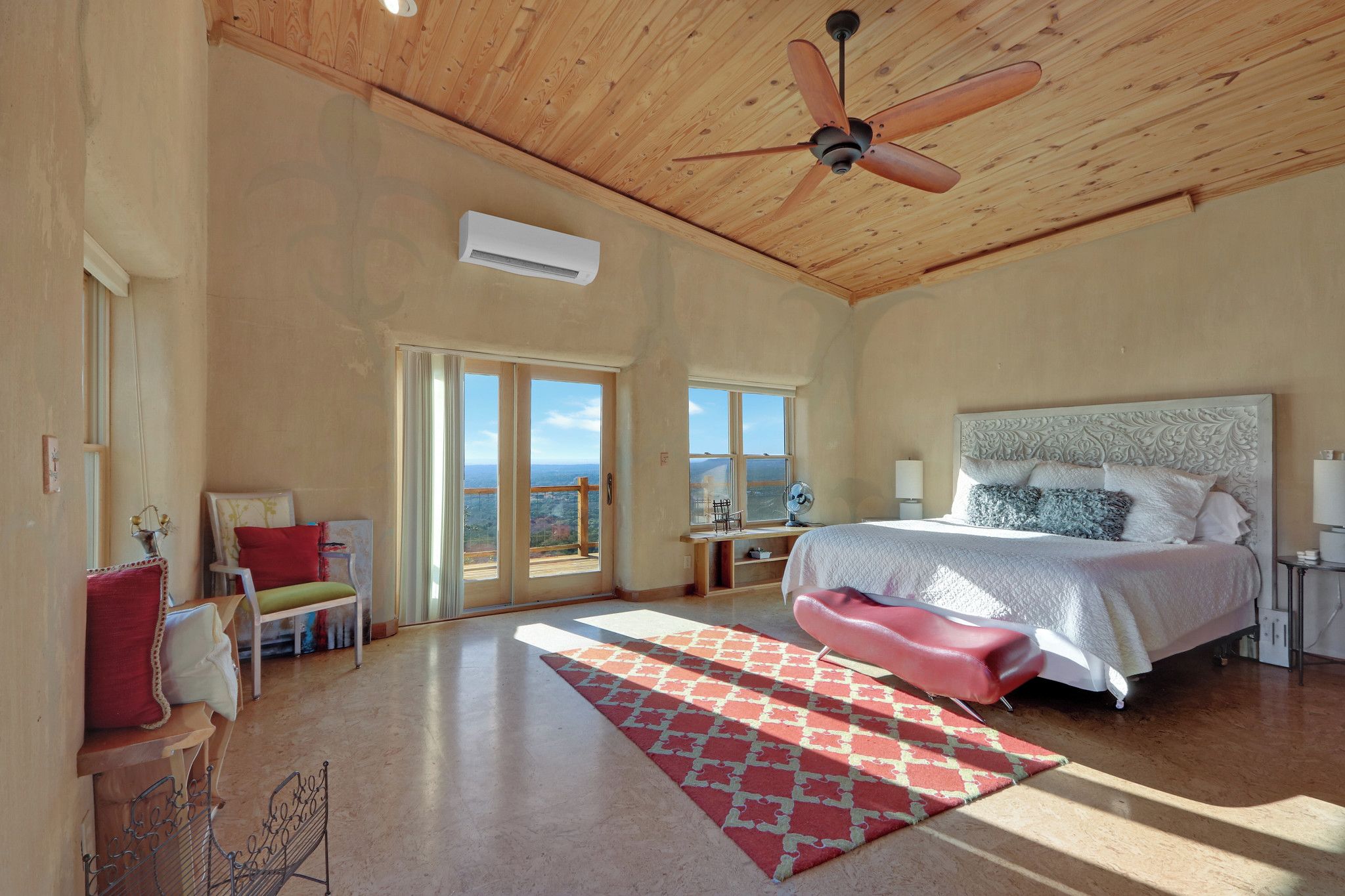 Un dormitorio amplio con una cama grande, un ventilador de techo y vistas a través de puertas de cristal.